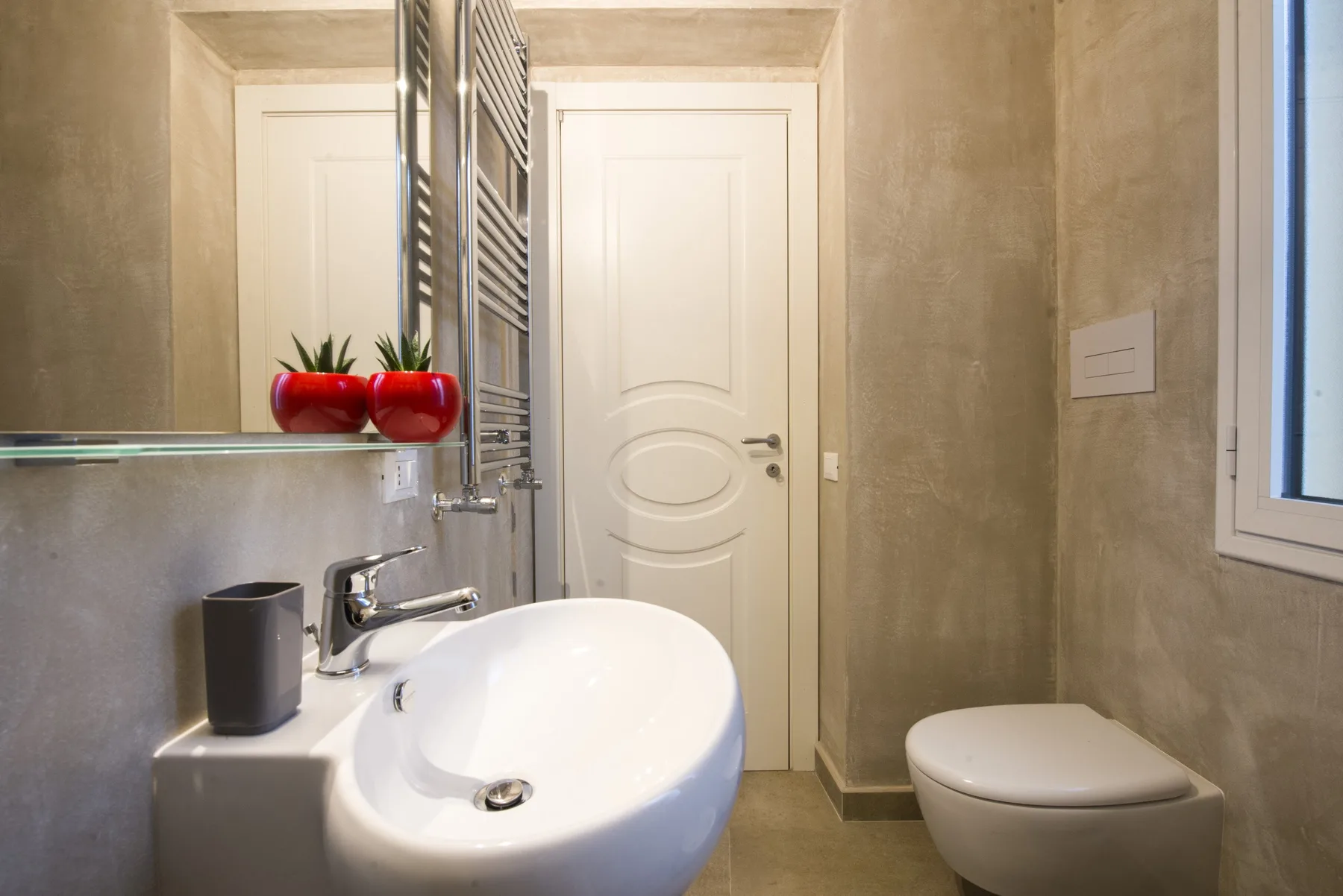 Un baño con lavabo blanco, inodoro y toallero calefactable en la pared.
