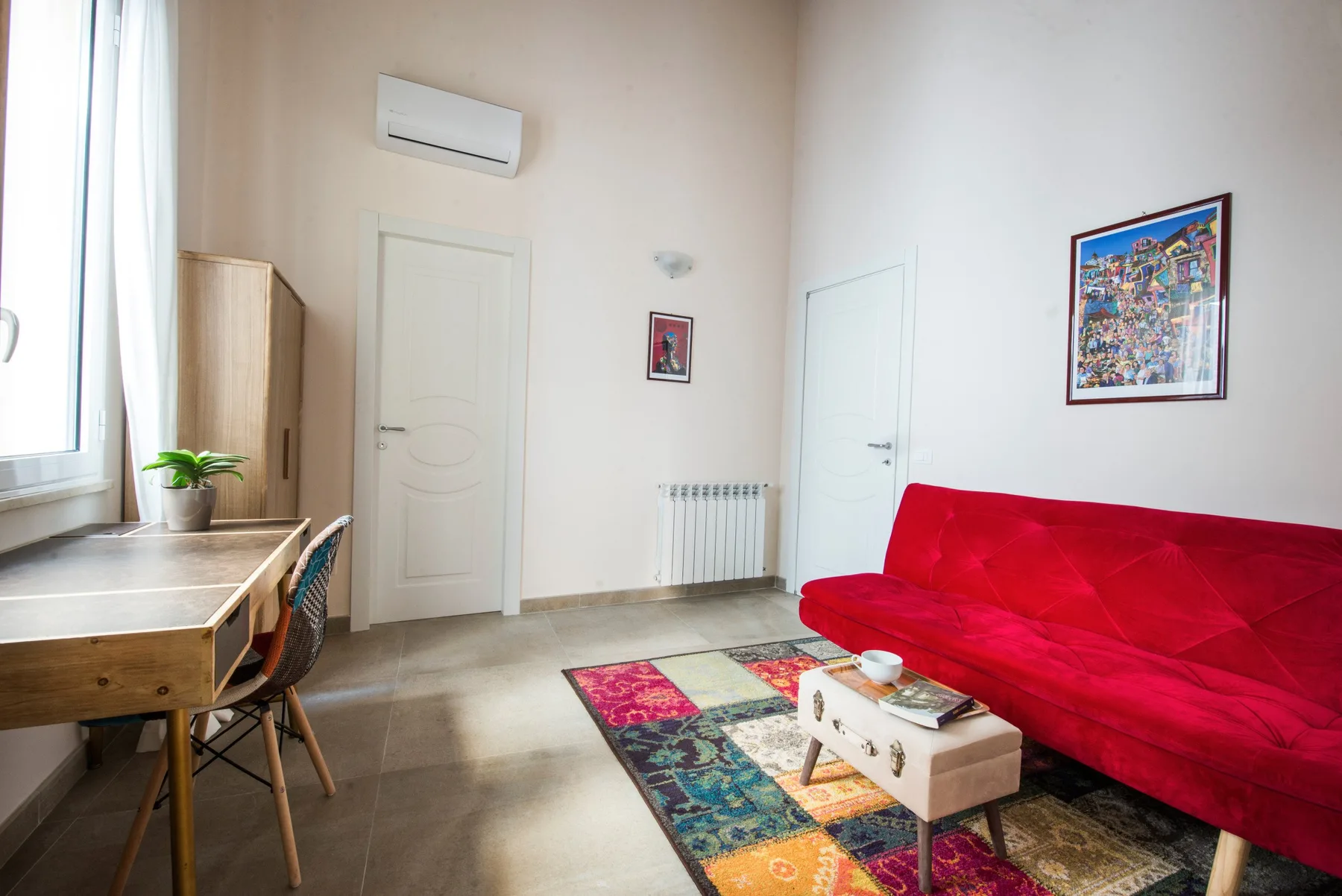 Una sala luminosa con asientos rojos y una alfombra colorida estampada.