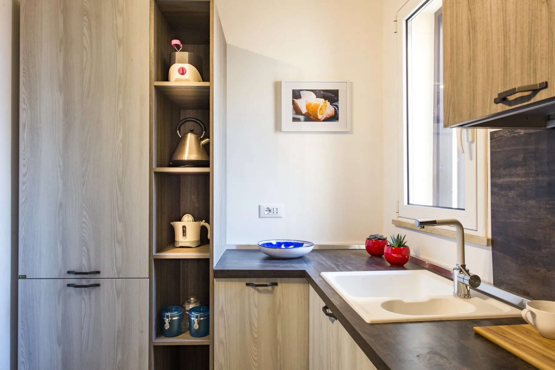 Una encimera de cocina con fregadero, armarios y una ventana.