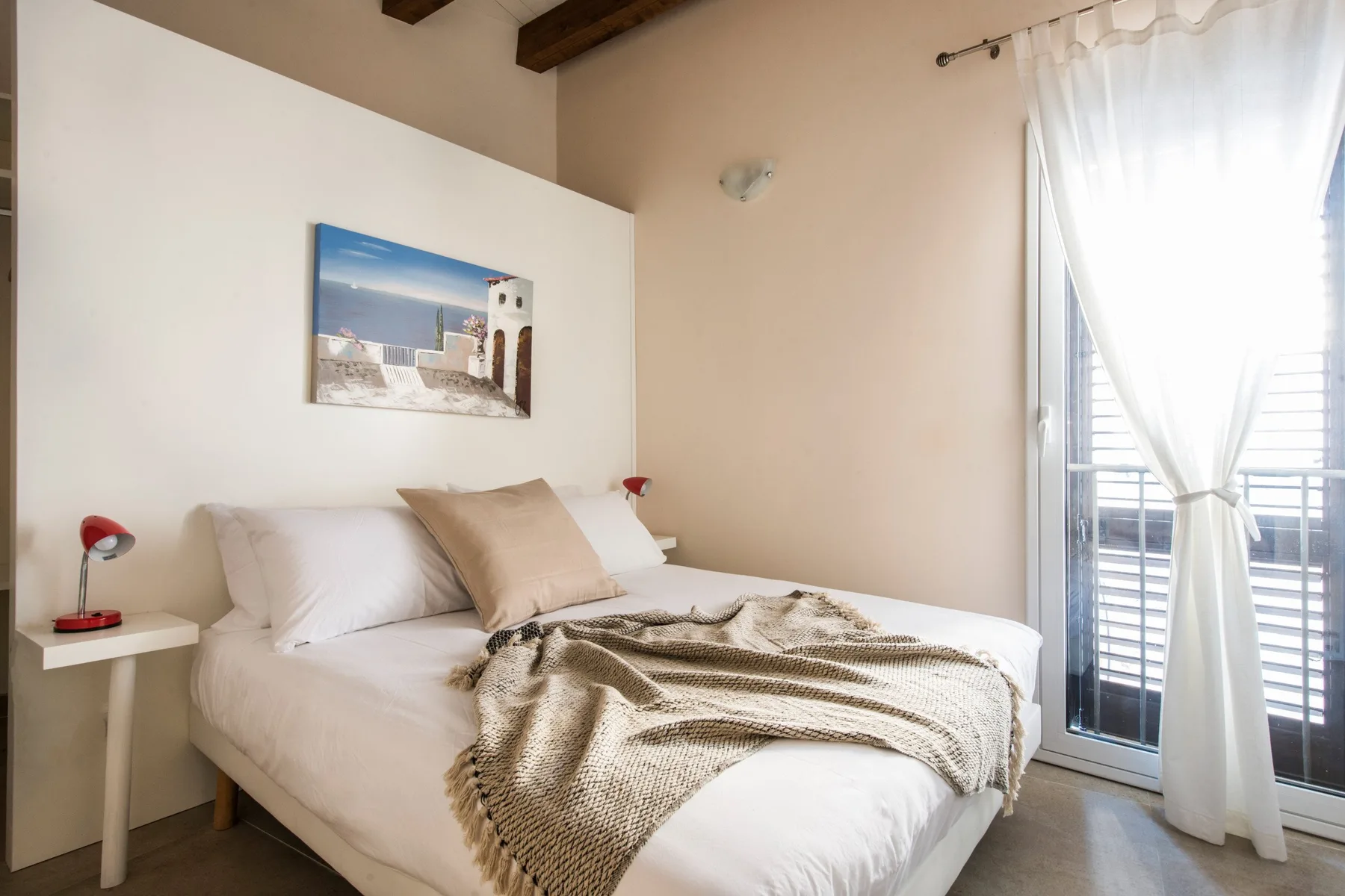 Un dormitorio luminoso con una cama y una puerta de vidrio con cortinas.
