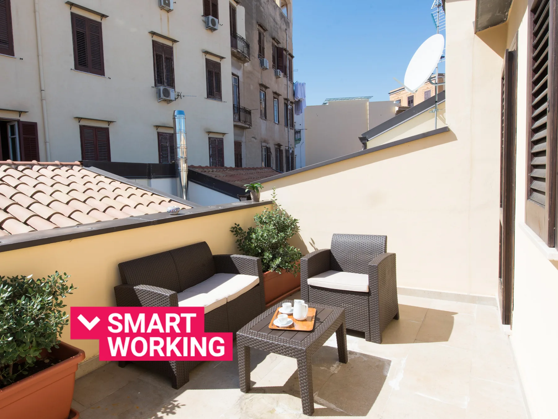 Una terraza soleada en la azotea con asientos al aire libre y plantas en macetas.