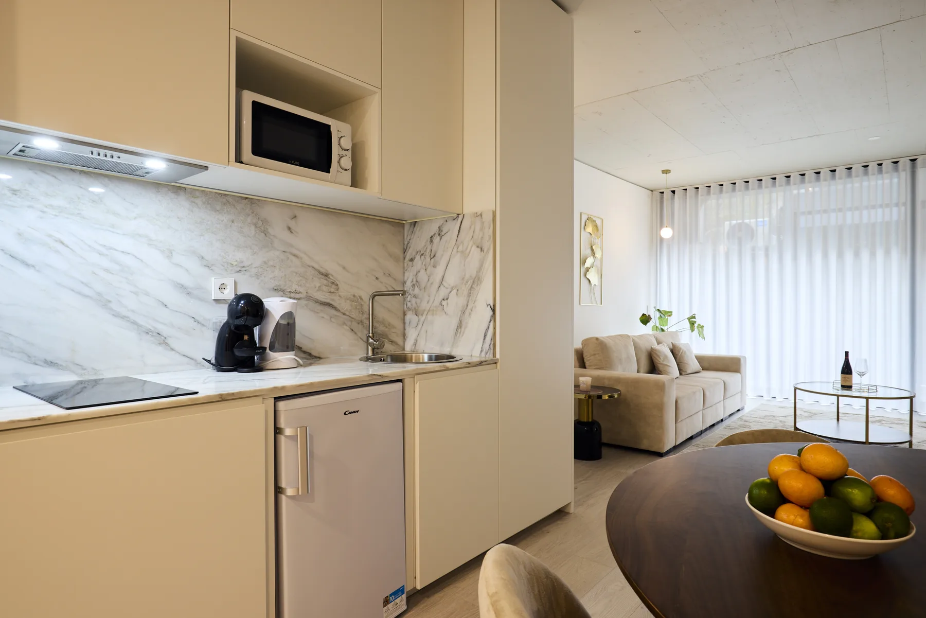 An open-plan kitchen and living area with a sofa and fruit bowl.
