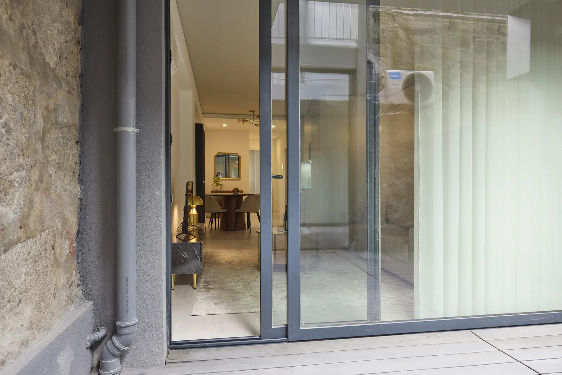 A glass sliding door opens onto a bright interior with a dining area.