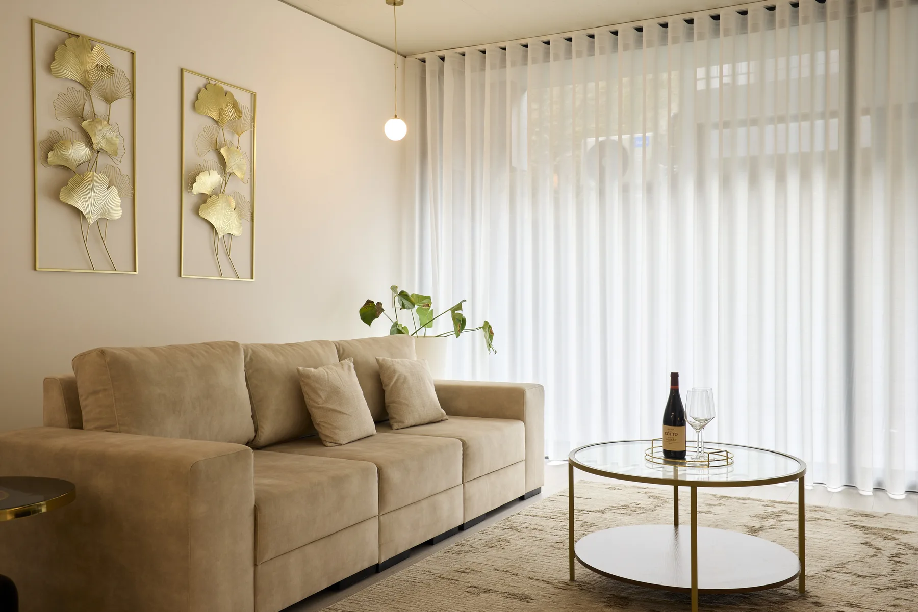 A living room with beige seating and a round glass coffee table.