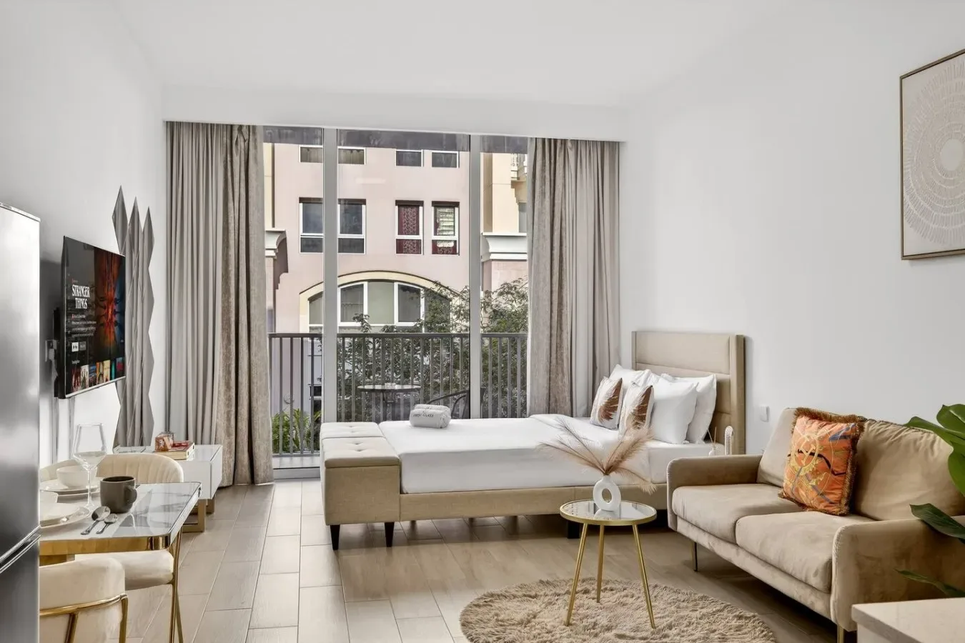 A bright living room with a bed, seating, and a large window.