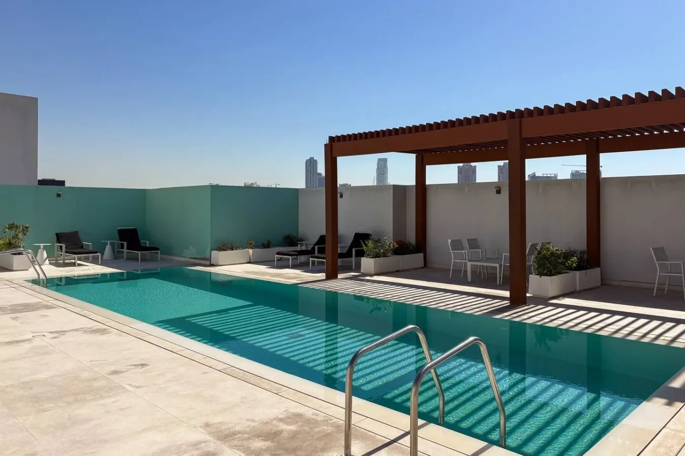 A rooftop swimming pool sits beside a shaded pergola and outdoor seating.