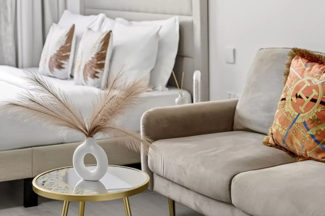 A bedroom and seating area with a bed, upholstered seating, and a small table.