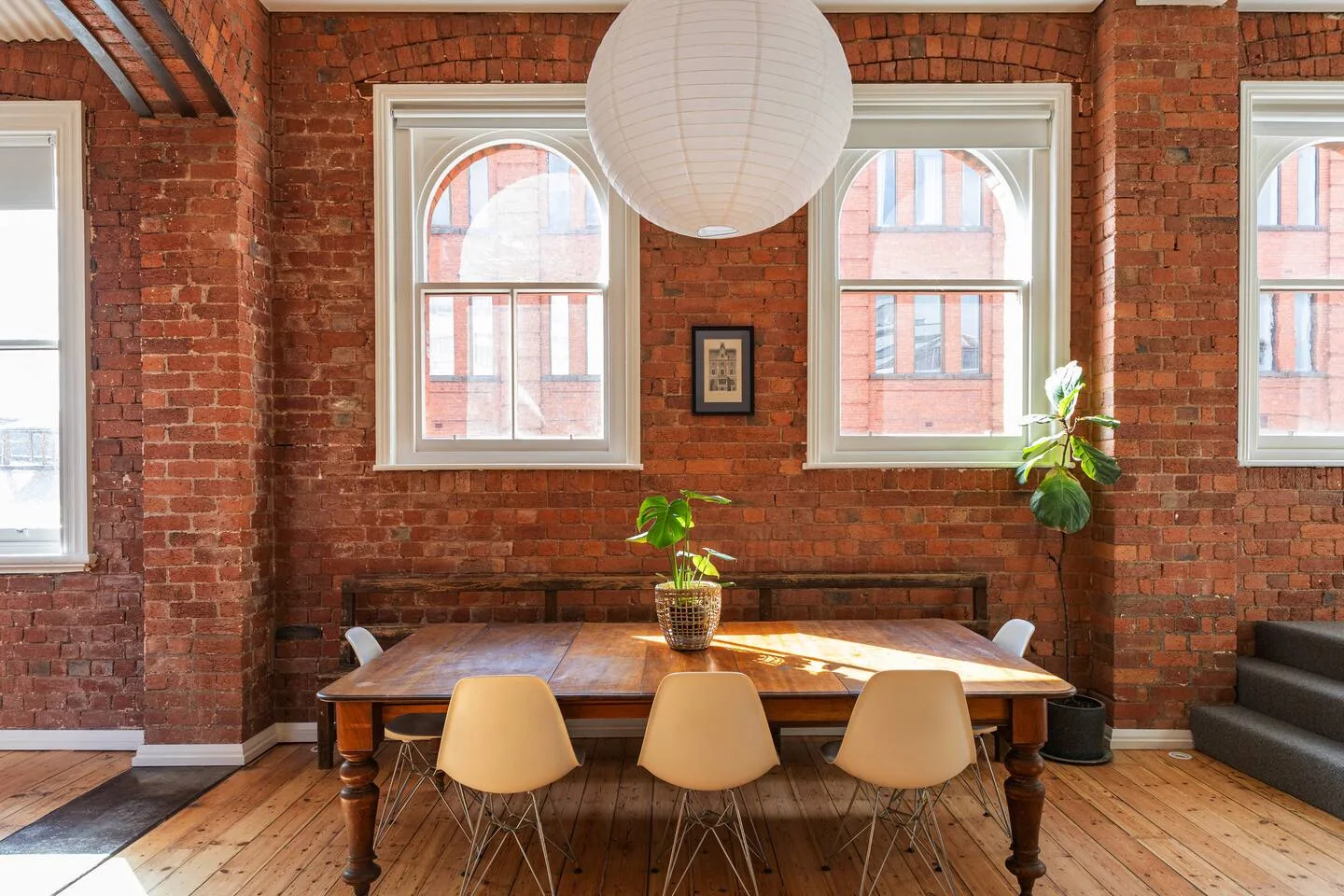 Una zona de comedor con una mesa de madera y asientos junto a paredes de ladrillo visto.