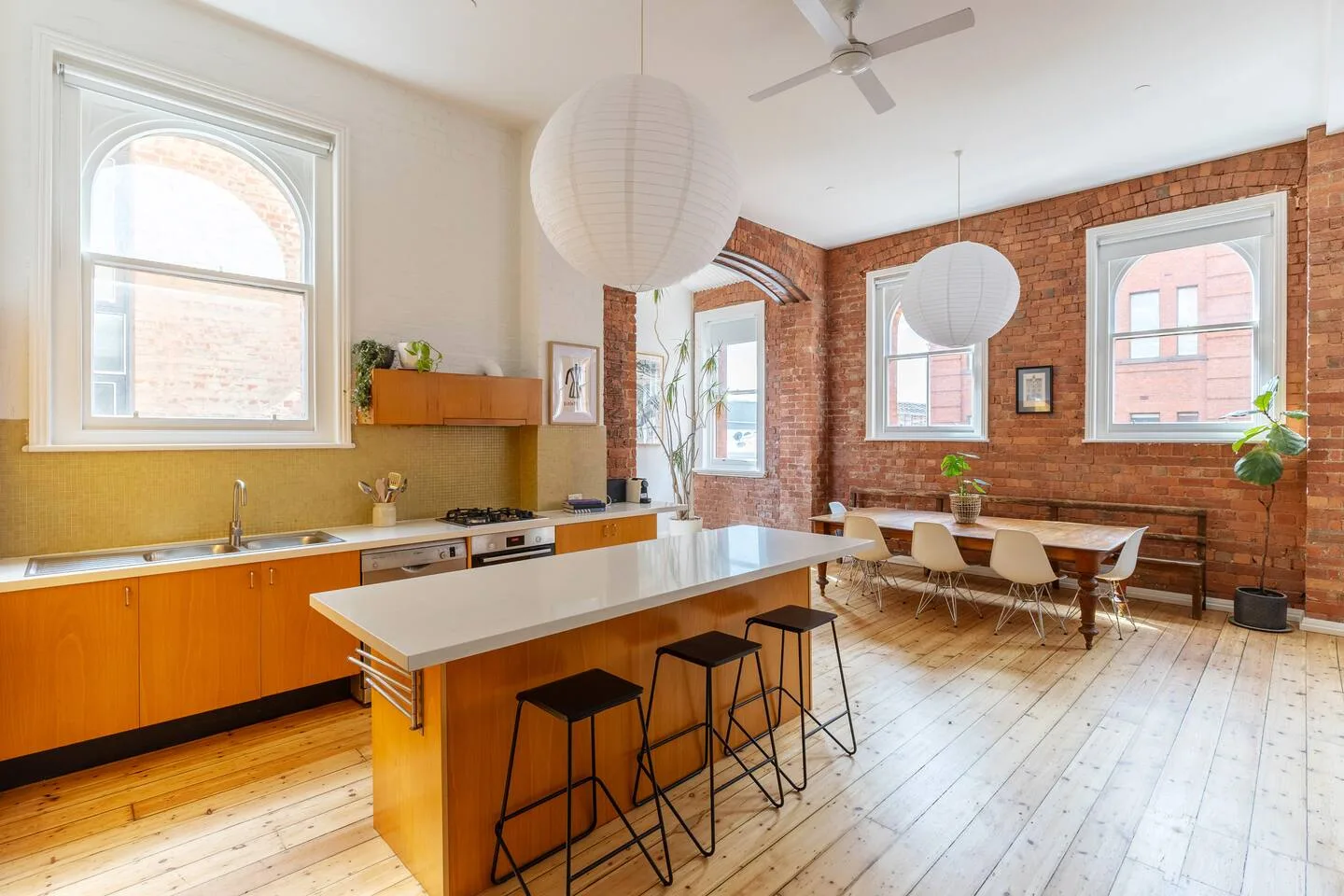 Una cocina luminosa con una isla y una mesa de comedor junto a paredes de ladrillo.