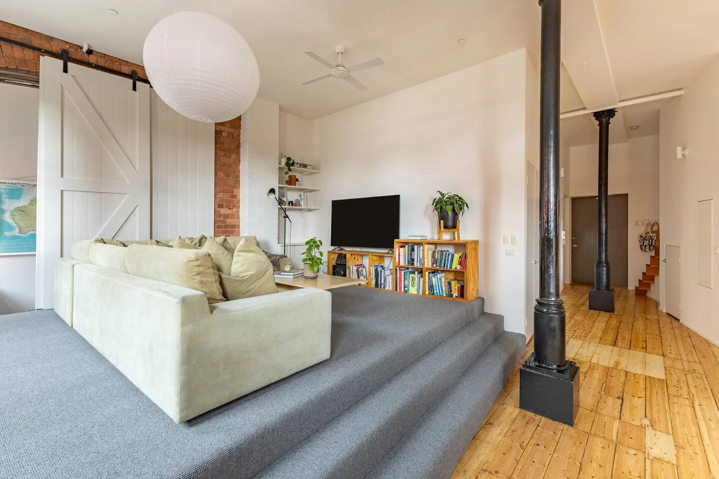 Una sala de estar con asientos, un televisor y piso de madera.