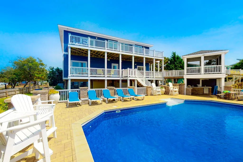 Una gran piscina al aire libre está junto a una casa de varios niveles.