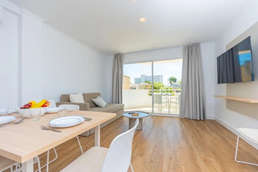 A bright living and dining area opens onto a balcony through sliding glass doors.