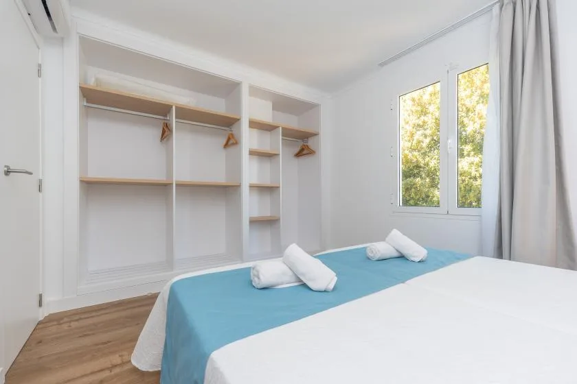 A bright bedroom with a bed, folded towels, and open shelving.