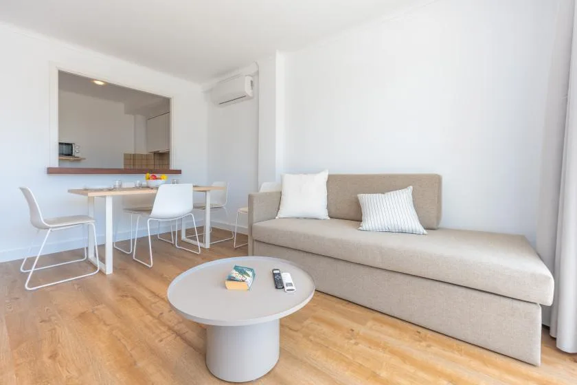 A bright living and dining area with a sofa, table, and seating.