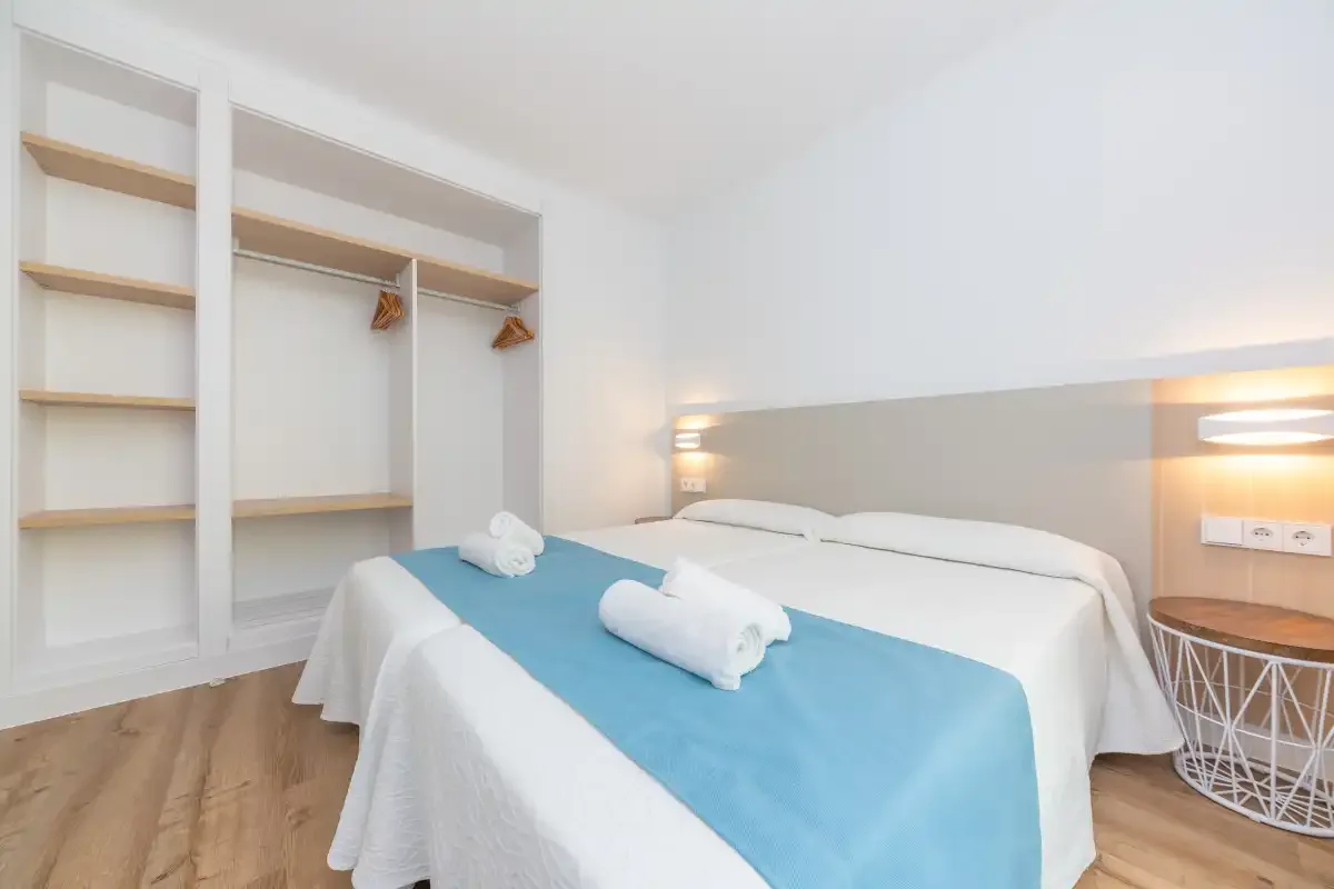 A bright bedroom with a double bed and open built-in shelving.