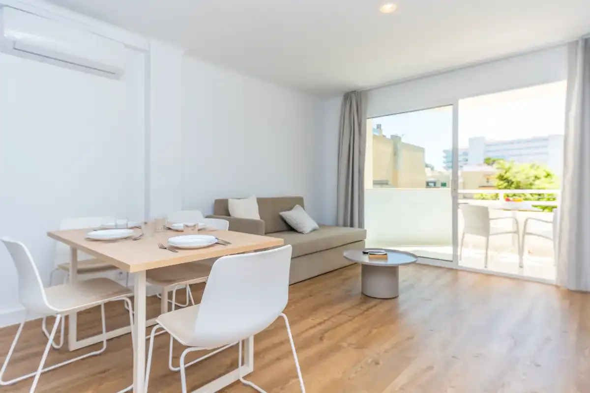 A bright living and dining area opens onto a balcony through large glass doors.