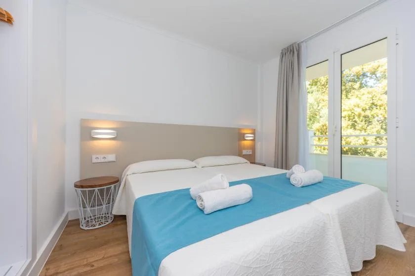 A bright bedroom with a bed dressed in white linens and a blue cover.