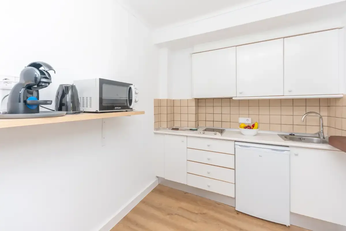 A bright kitchen with white cabinets, a countertop, and small appliances.