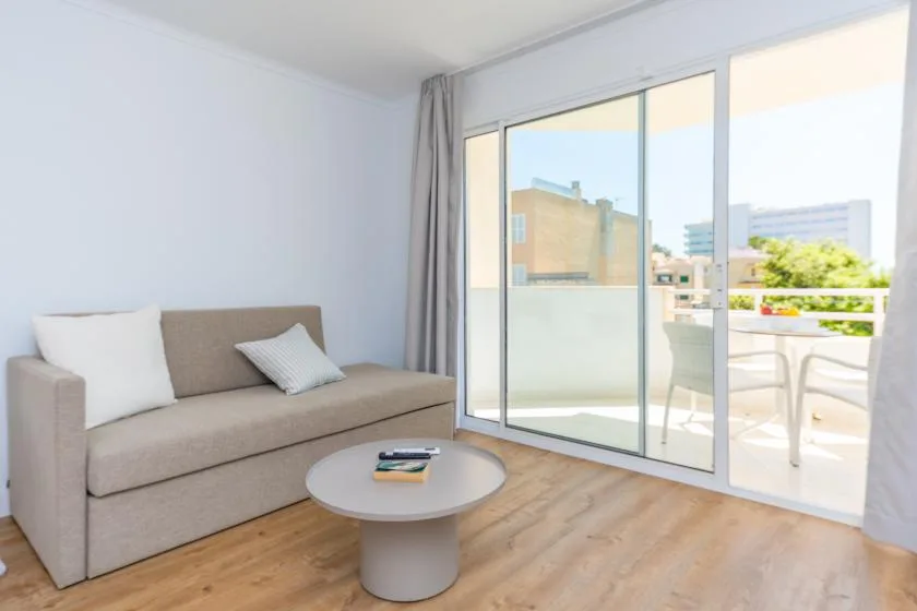 A bright living room with a sofa, coffee table, and sliding glass doors to a balcony.