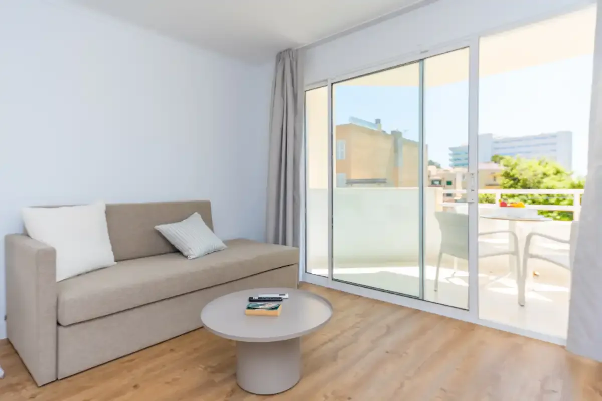 A bright living area with a sofa and a sliding glass door opening onto a balcony.