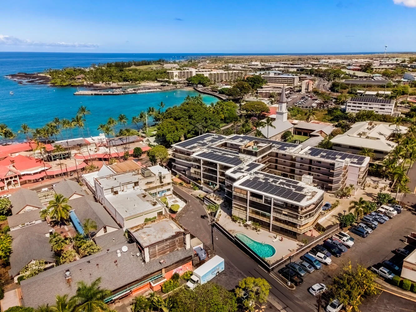 Vista aérea de un vecindario costero con edificios, una bahía y una piscina.