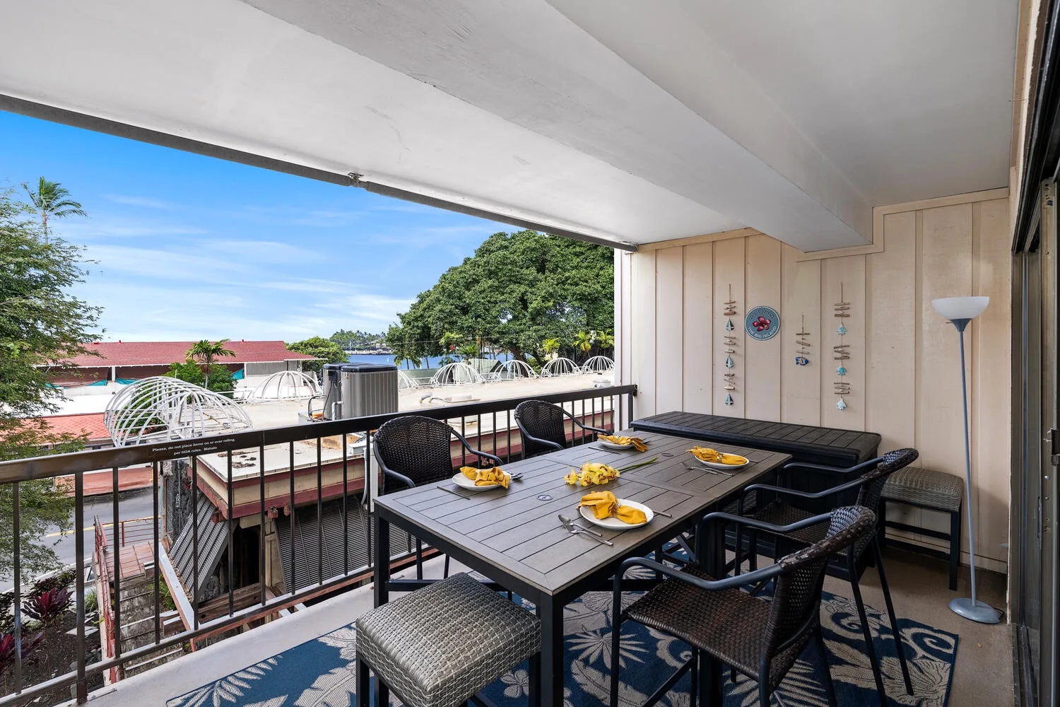 Una zona cubierta de comedor al aire libre tiene una mesa y asientos junto a una barandilla.