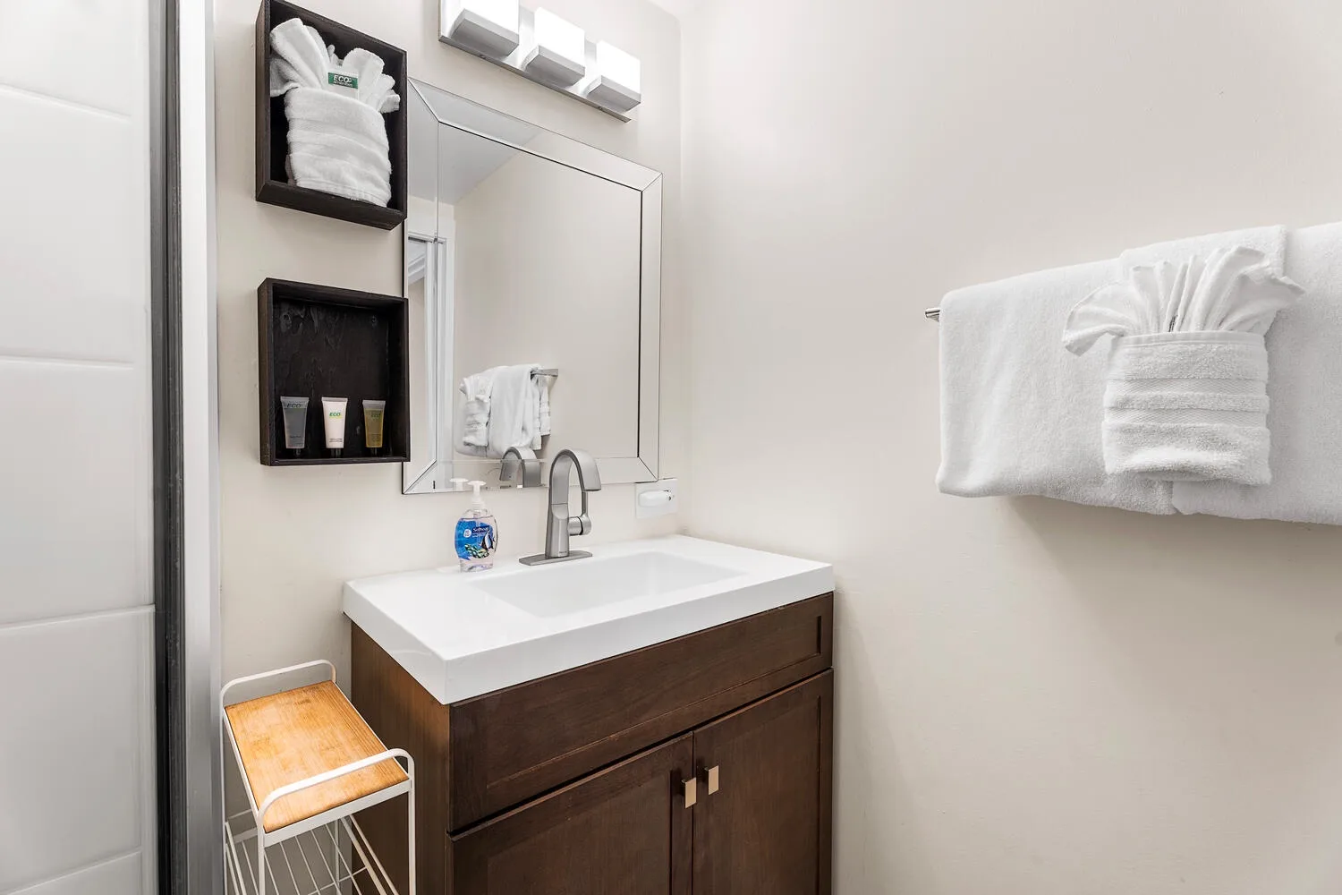 Un tocador de baño con lavabo y espejo junto a un toallero.