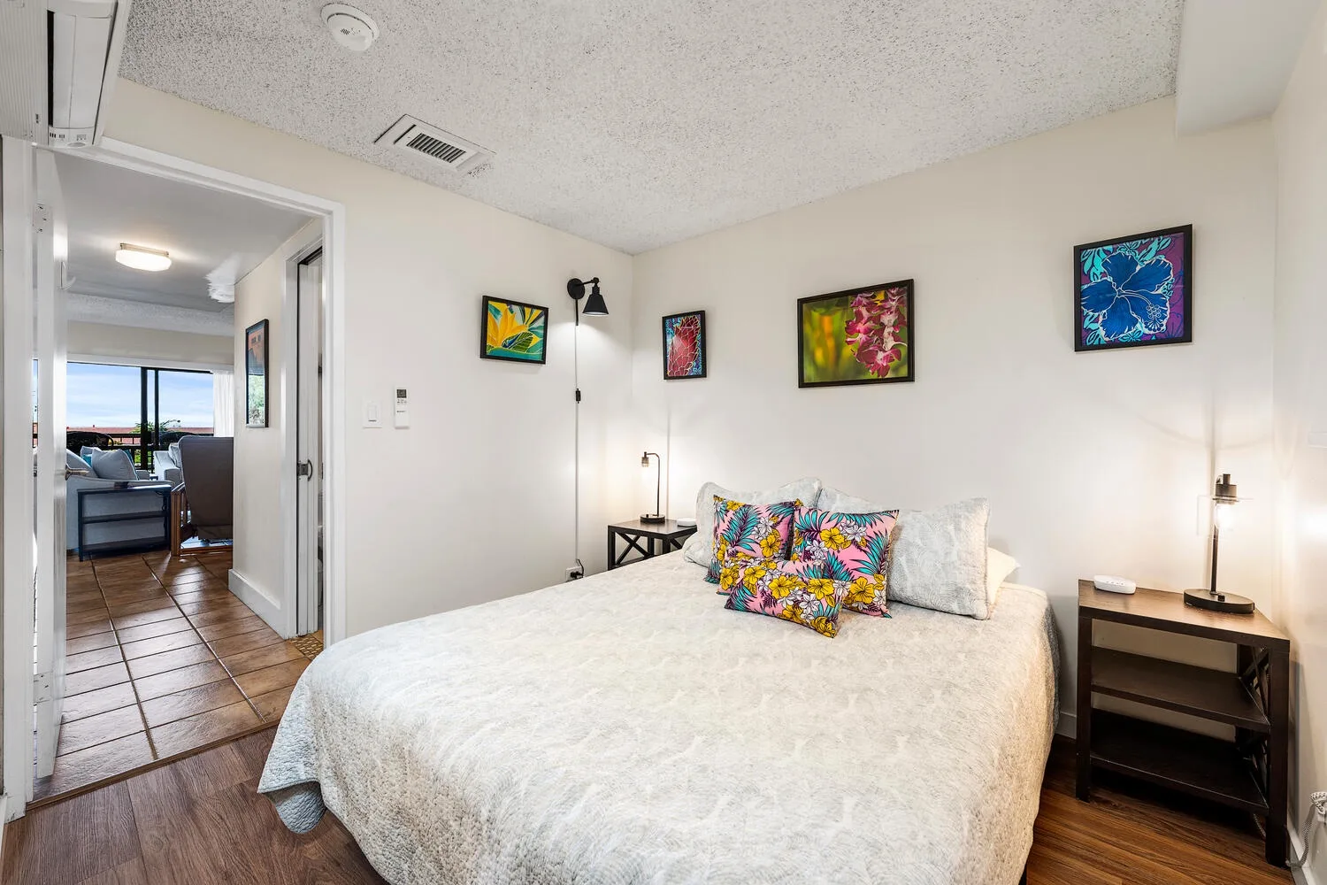 Un dormitorio con una cama, cojines coloridos y cuadros en las paredes.