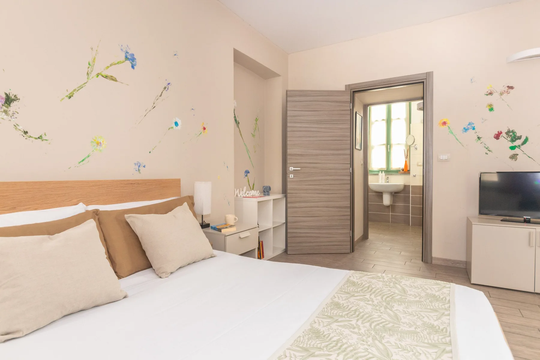 Un dormitorio con cama doble, mesitas de noche y una puerta al baño.