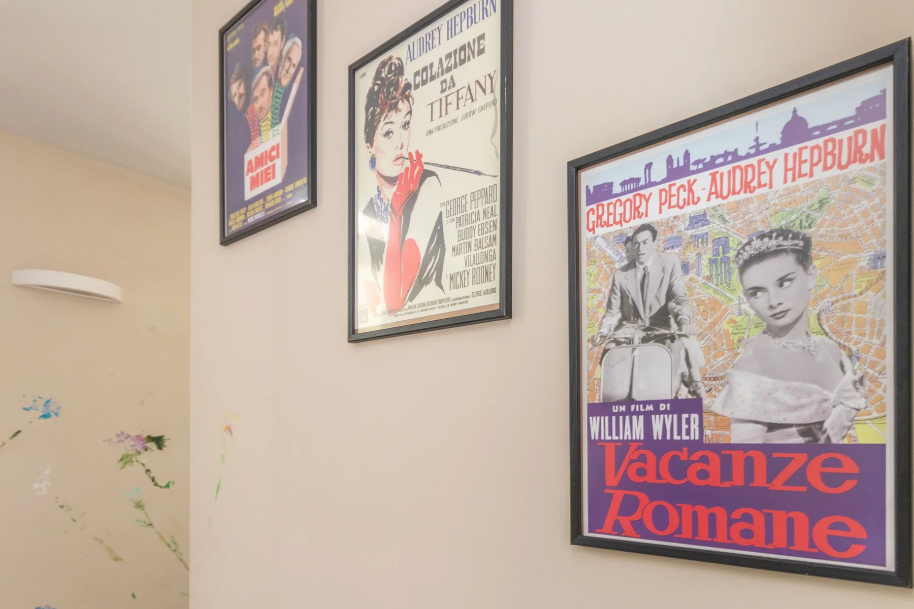 Una pared interior de color claro muestra varios carteles de cine antiguos enmarcados.