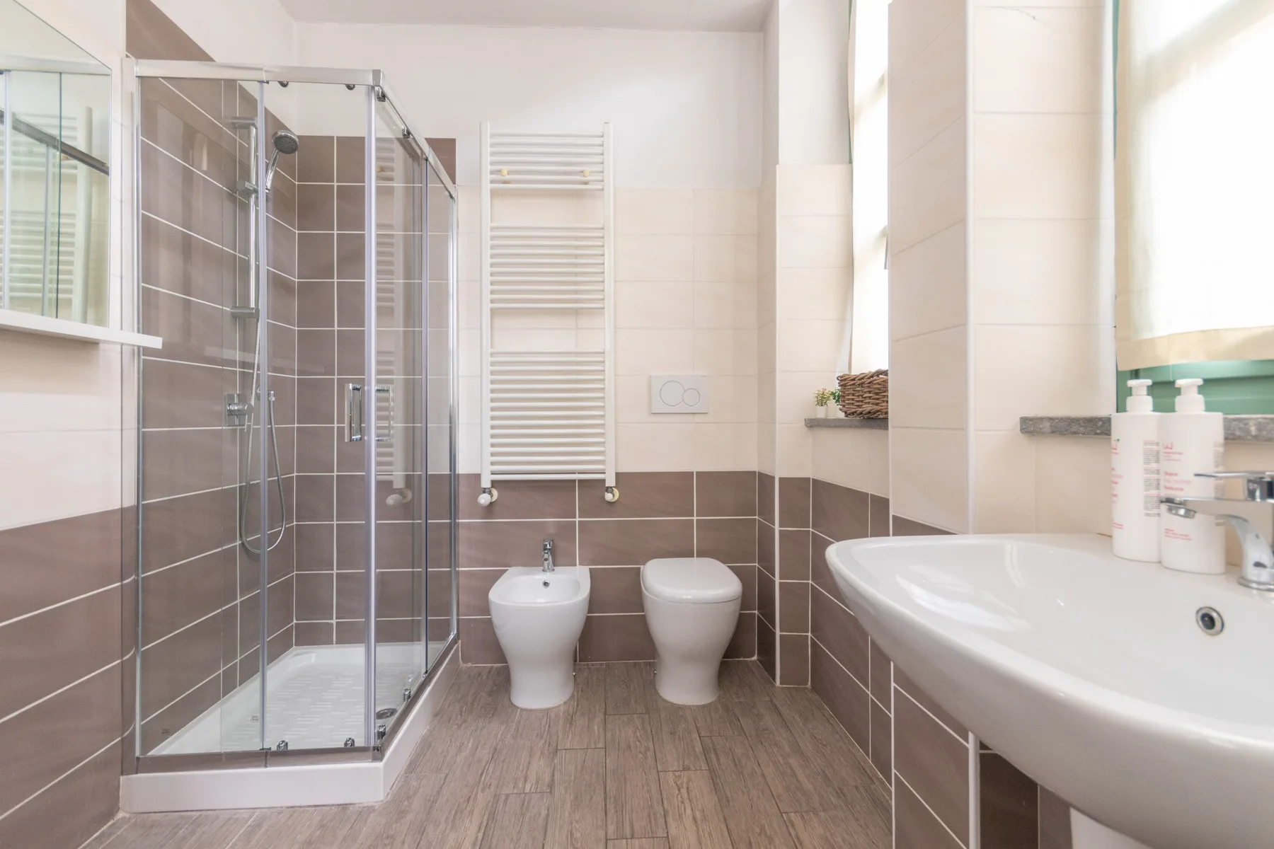 Un baño alicatado con ducha de vidrio, inodoro y lavabo.
