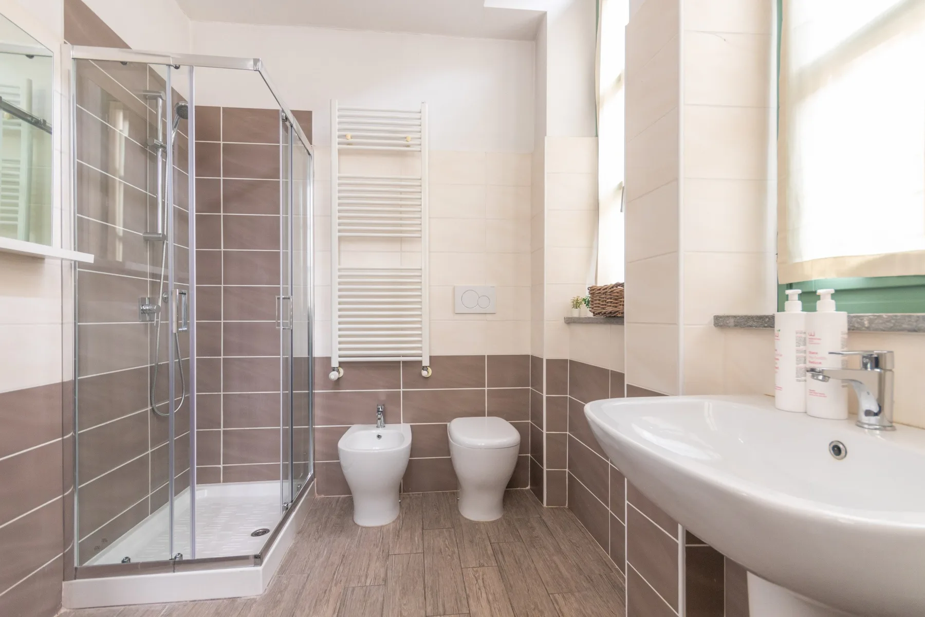 Un baño luminoso con ducha de vidrio, inodoro y lavabo.