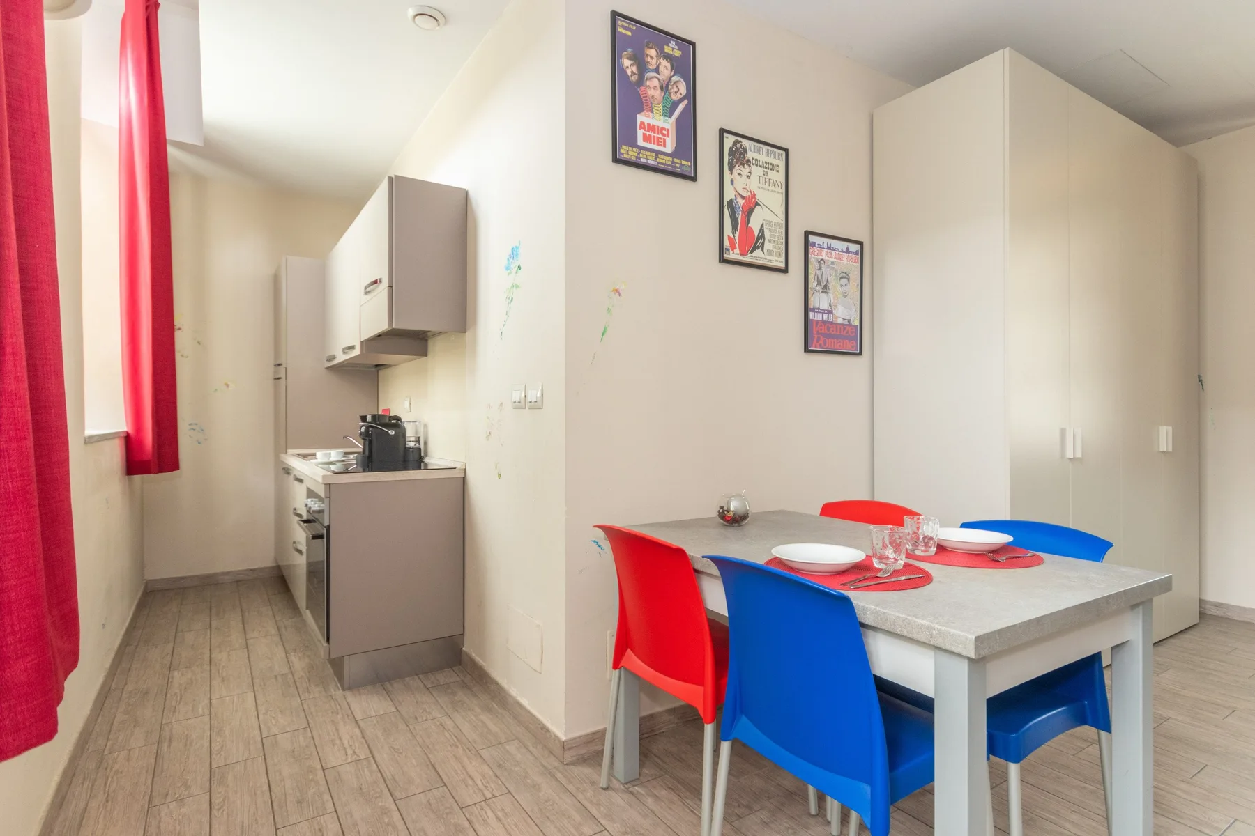 Un comedor con asientos de colores junto a una cocina compacta.