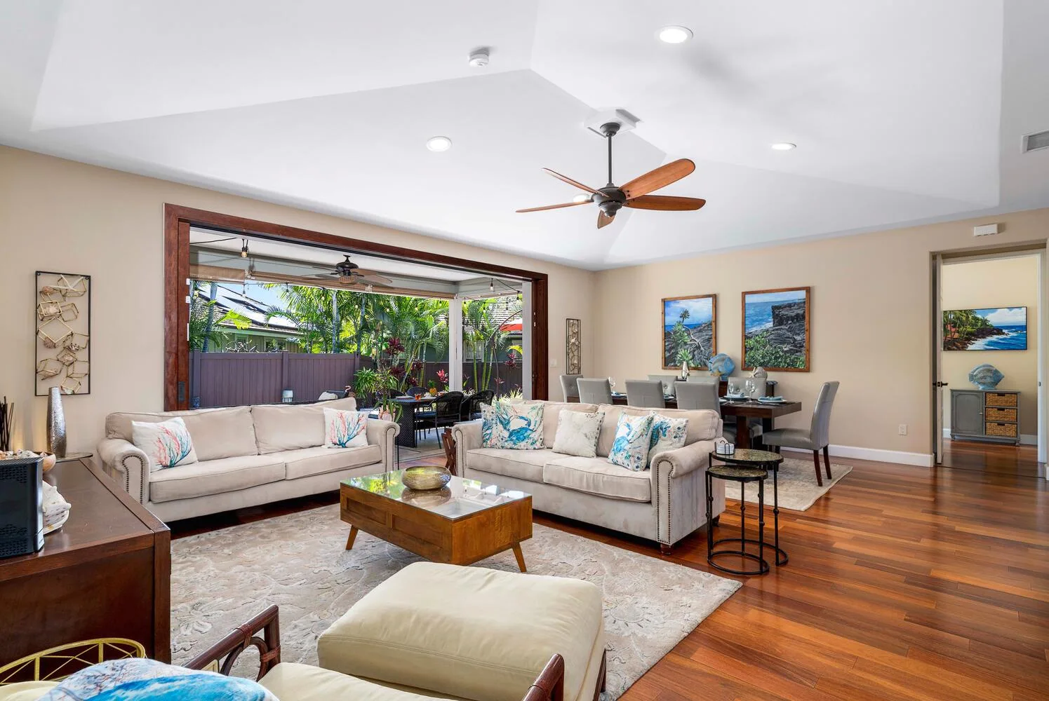 A bright living room opens onto a patio, with sofas arranged around a coffee table.