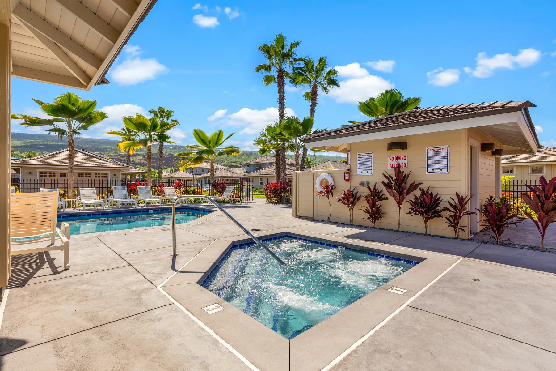 An outdoor pool area with a bubbling spa and palm trees under a blue sky.