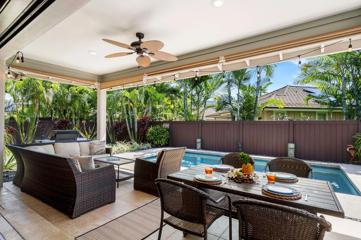 A covered outdoor patio with seating and a swimming pool.