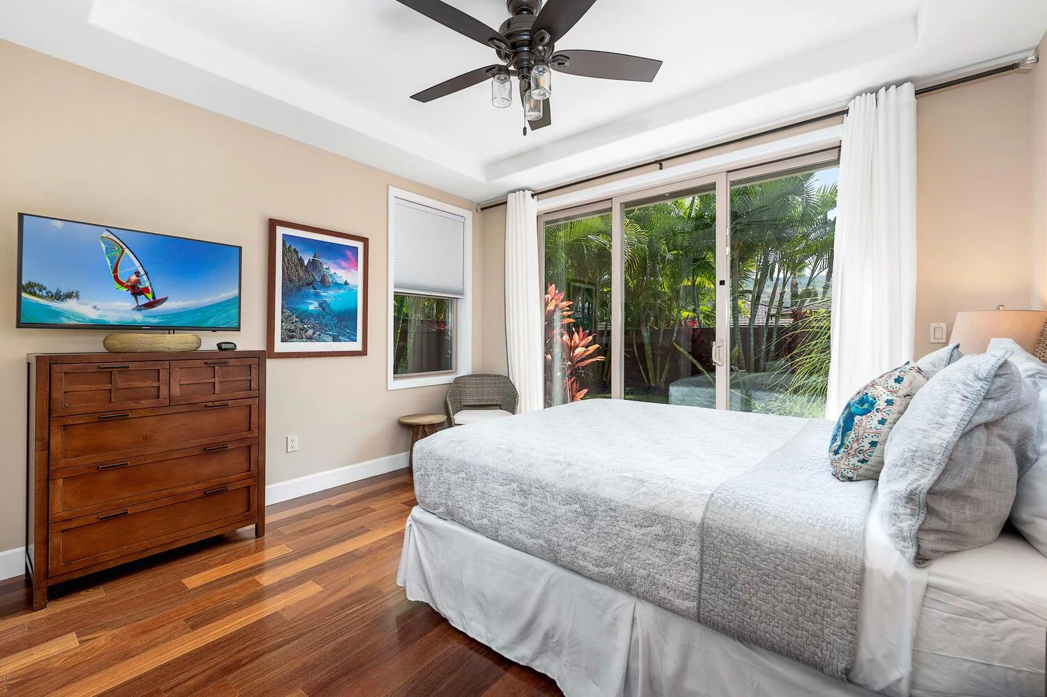 A bedroom with a bed beside large glass doors opening onto a leafy garden.