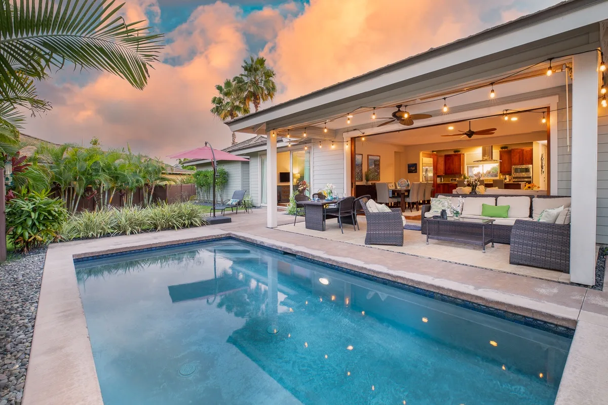 A swimming pool beside a covered patio with outdoor seating.
