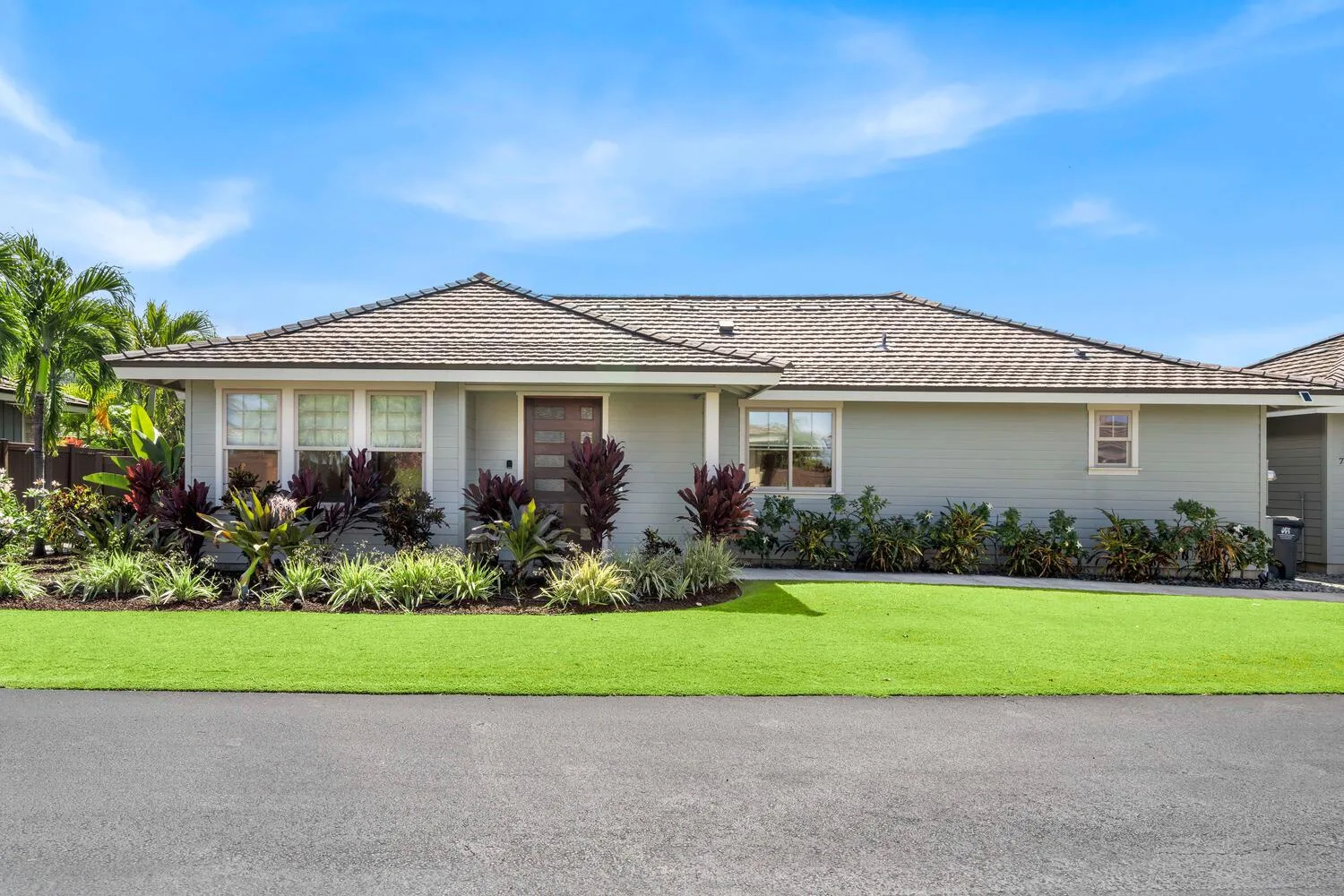 A single-story house with a tiled roof stands behind a green lawn.