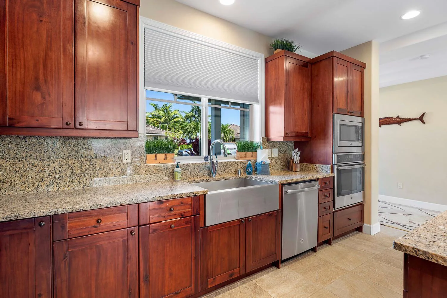 A kitchen with wooden cabinets, a sink, and a window overlooking greenery.