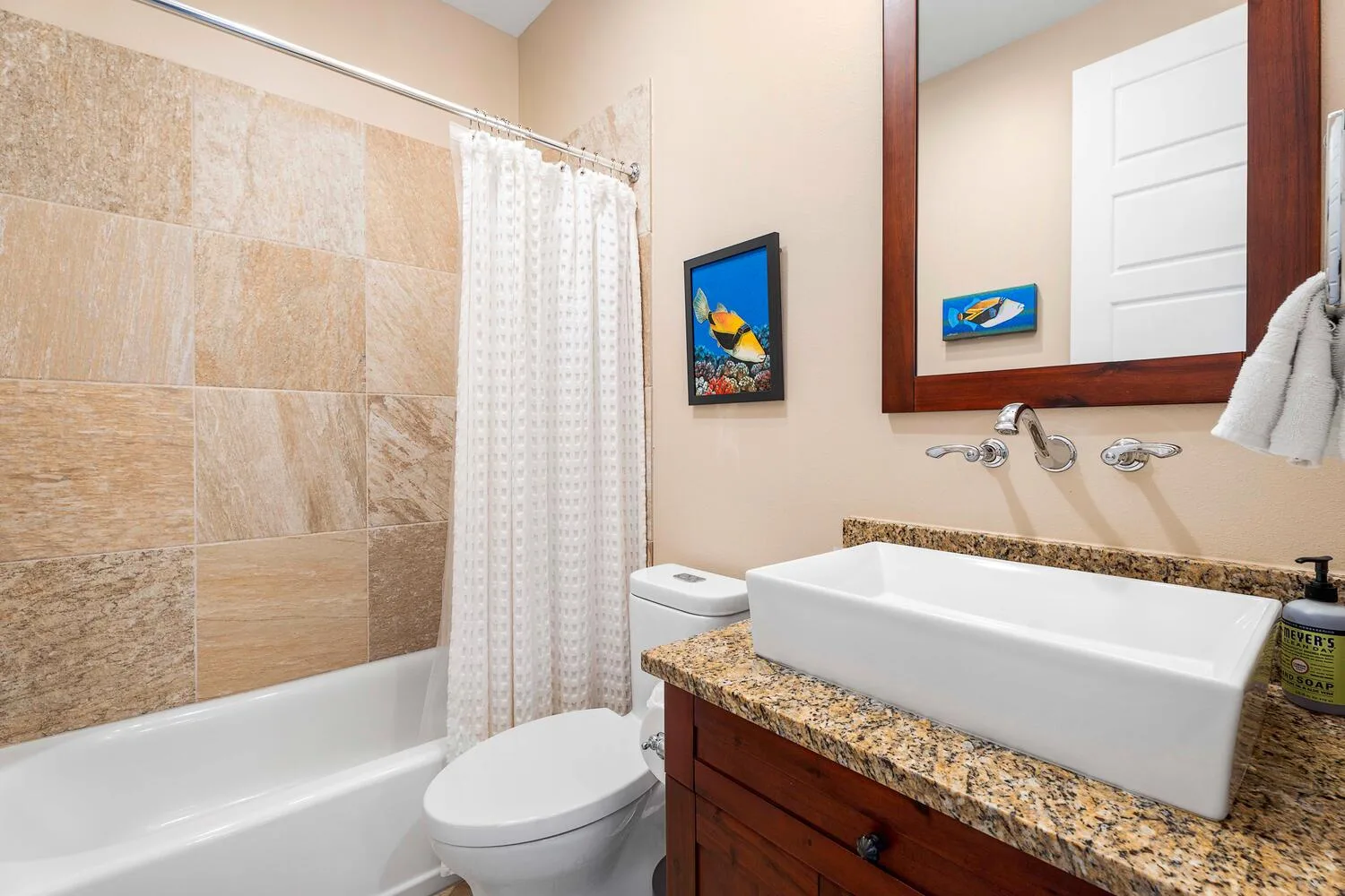 A bathroom with a bathtub, shower curtain, toilet, and sink.