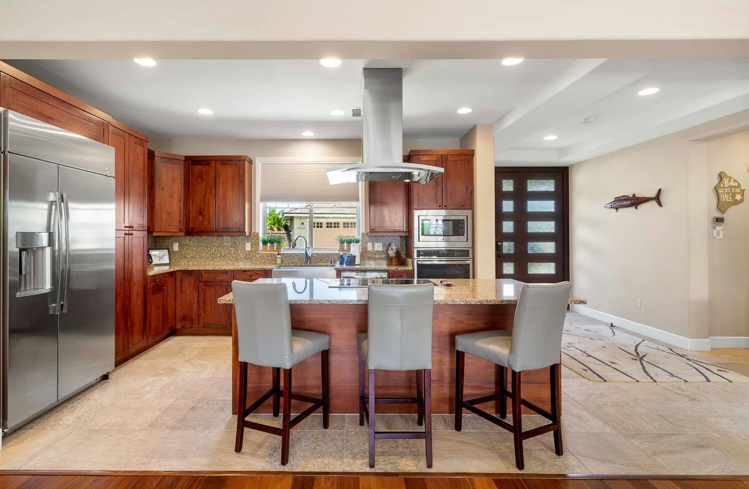 A kitchen with a central island and bar seating opens onto a dining area.