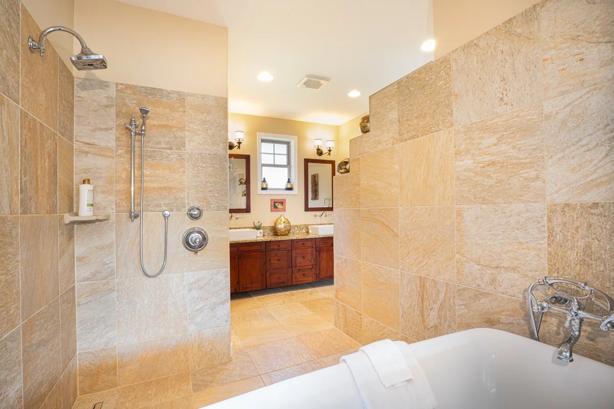 A tiled bathroom with a shower and a vanity beneath a window.