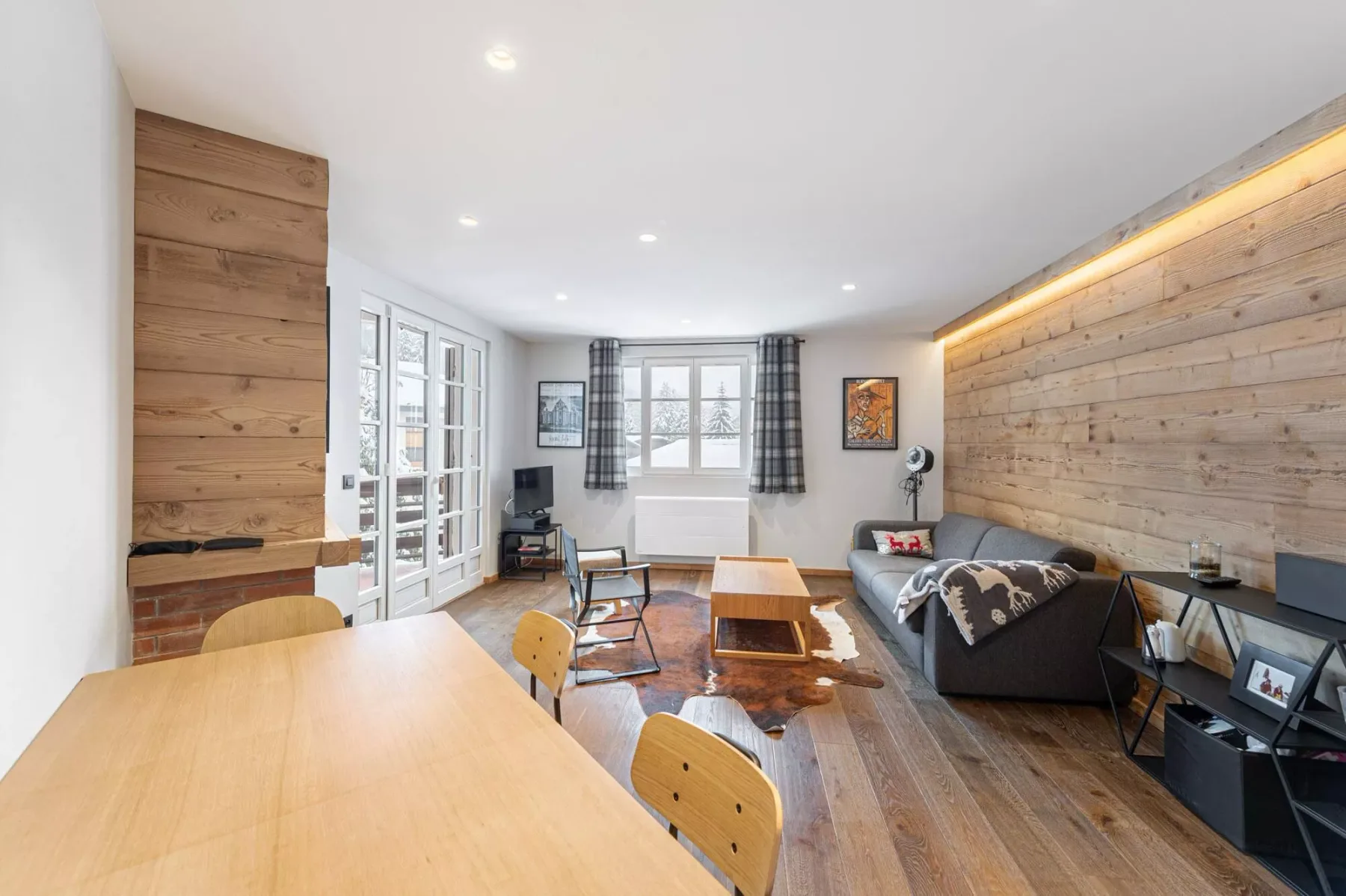 Una sala luminosa con asientos, una mesa de centro y una amplia mesa de comedor de madera.