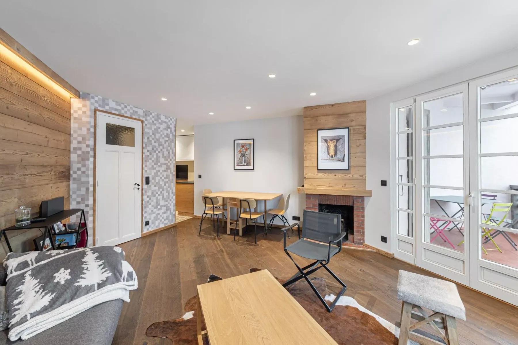Sala de estar con mesa de comedor y asientos junto a grandes puertas de vidrio.