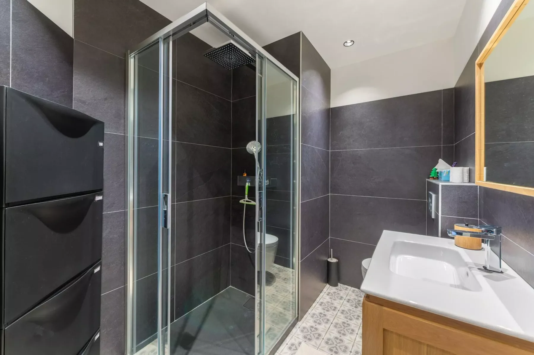 Un baño alicatado con una ducha de vidrio y un lavabo con mueble.