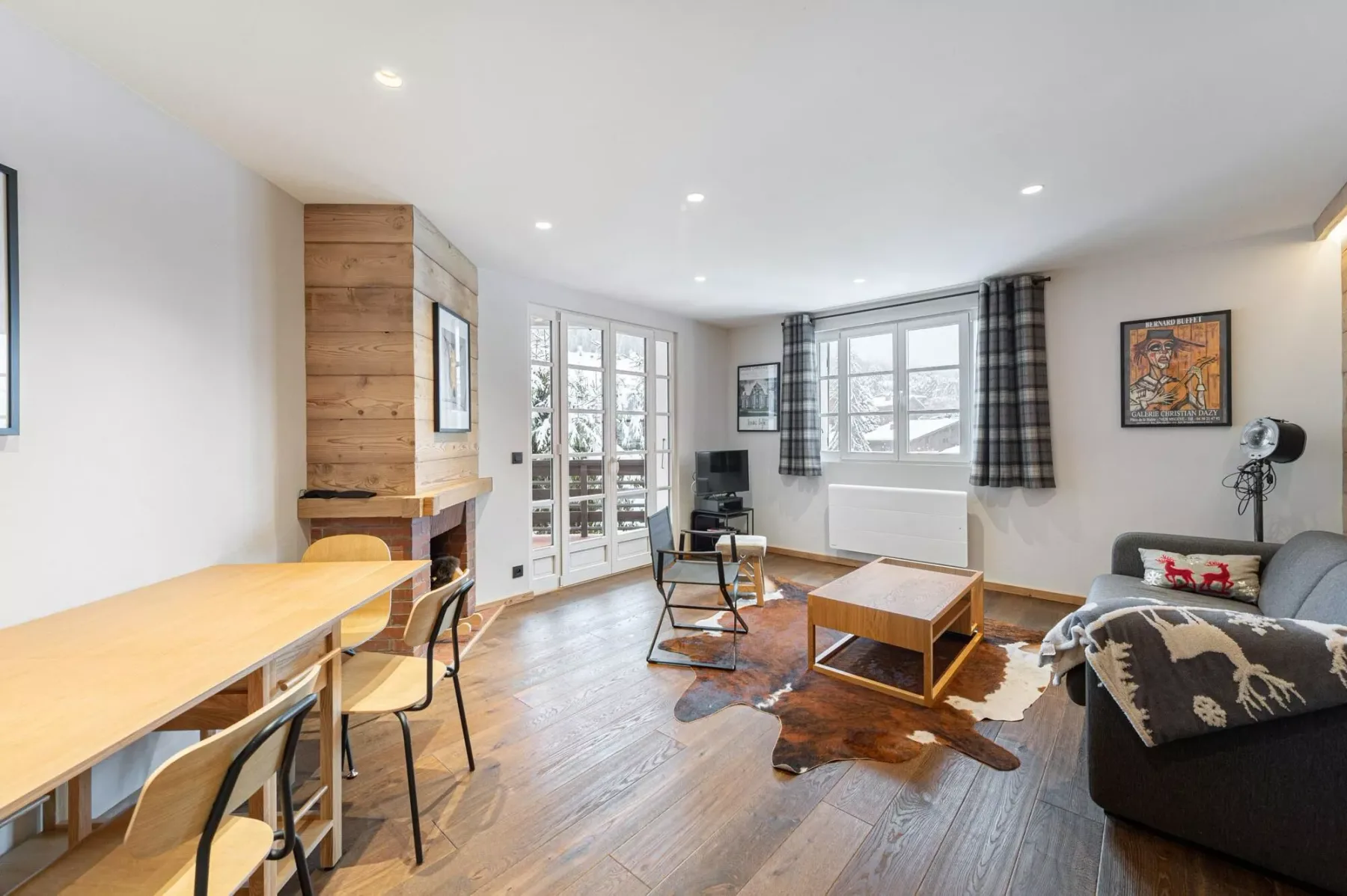 Una sala luminosa con asientos, una mesa de centro y ventanas grandes.