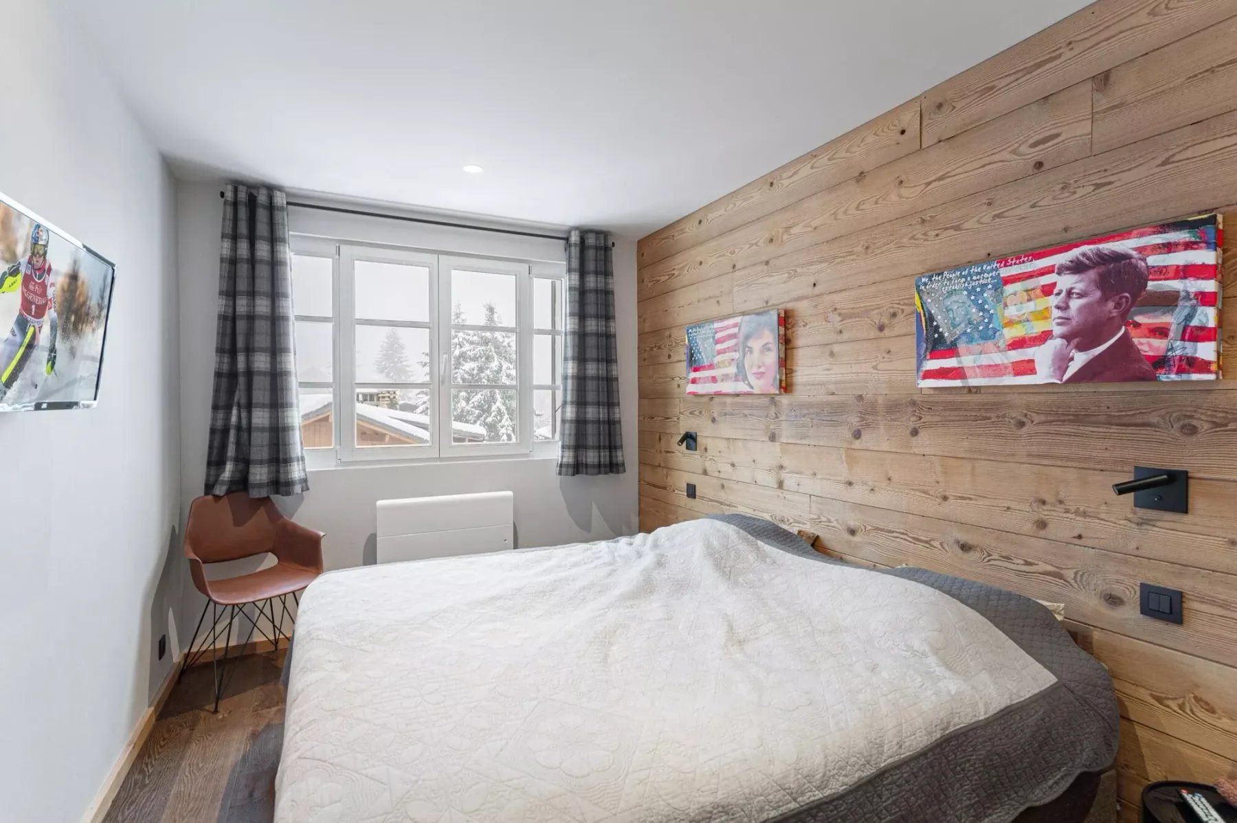 Un dormitorio con una cama, una ventana y una pared revestida de madera.