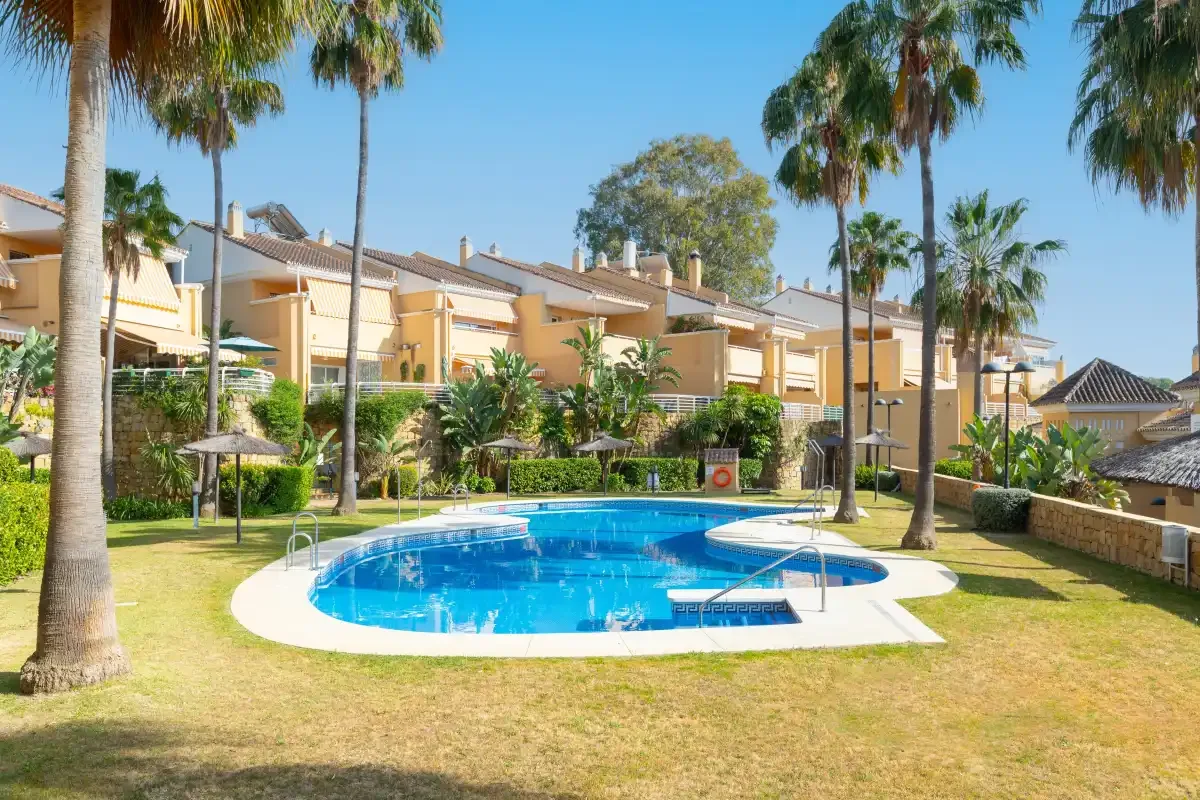 A residential complex with a curved outdoor pool surrounded by palm trees.