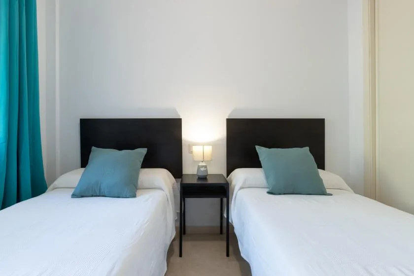 A bedroom with two single beds and a small table between them.